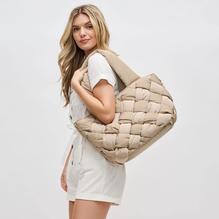 Woman carrying an oversized beige puffer tote