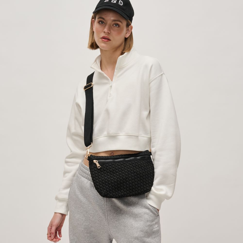 black crossbody purse slung across a woman’s shoulder