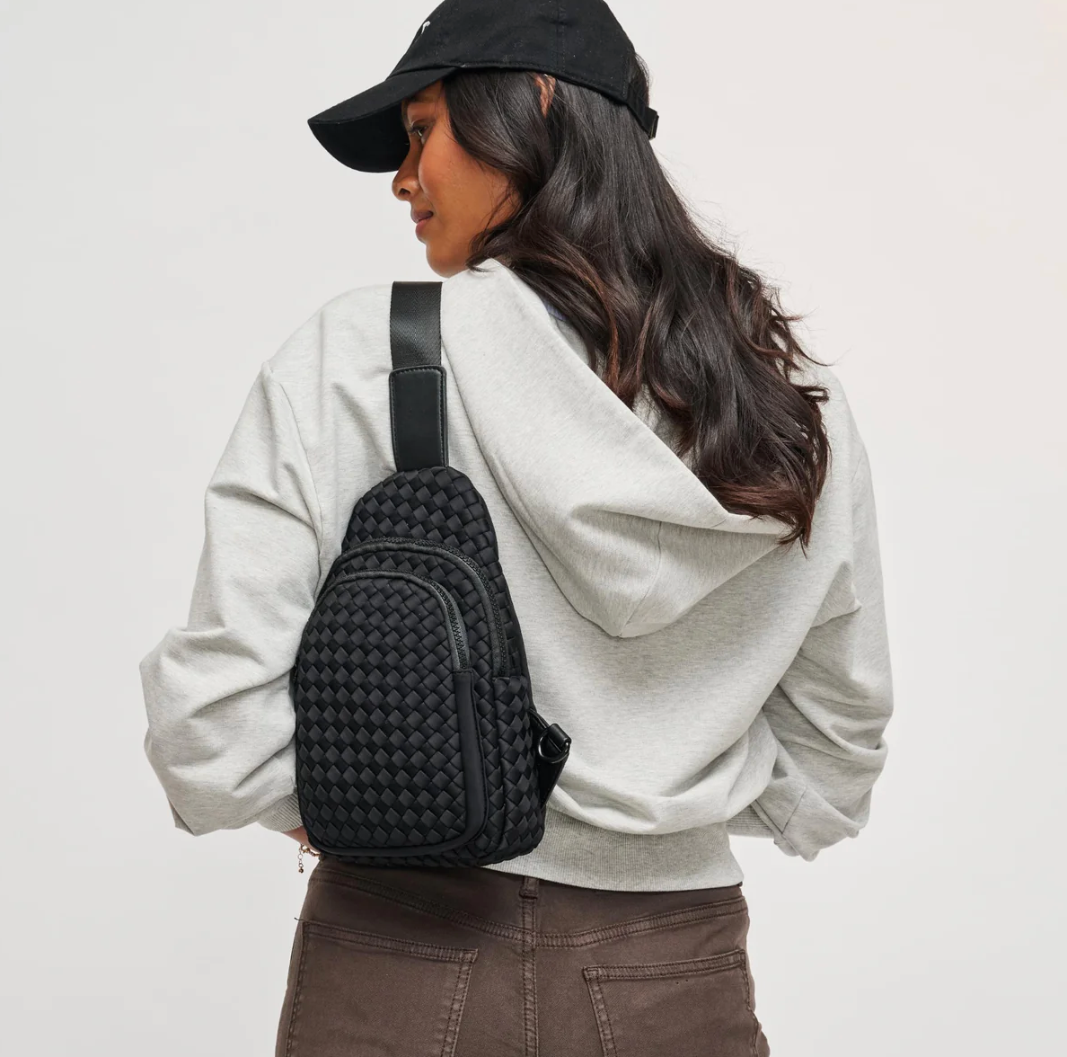 model wearing a black sling backpack