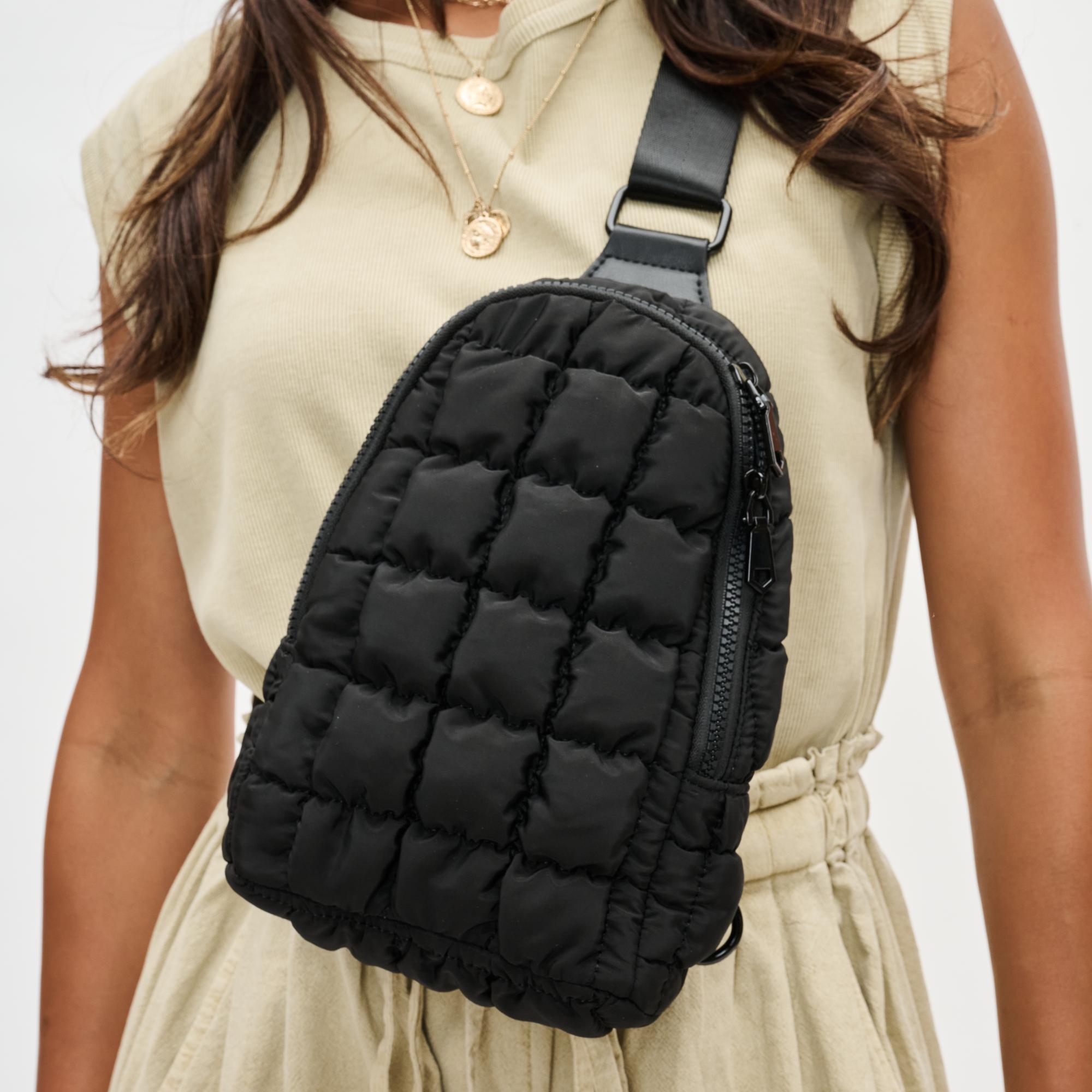 model wearing a black sling backpack