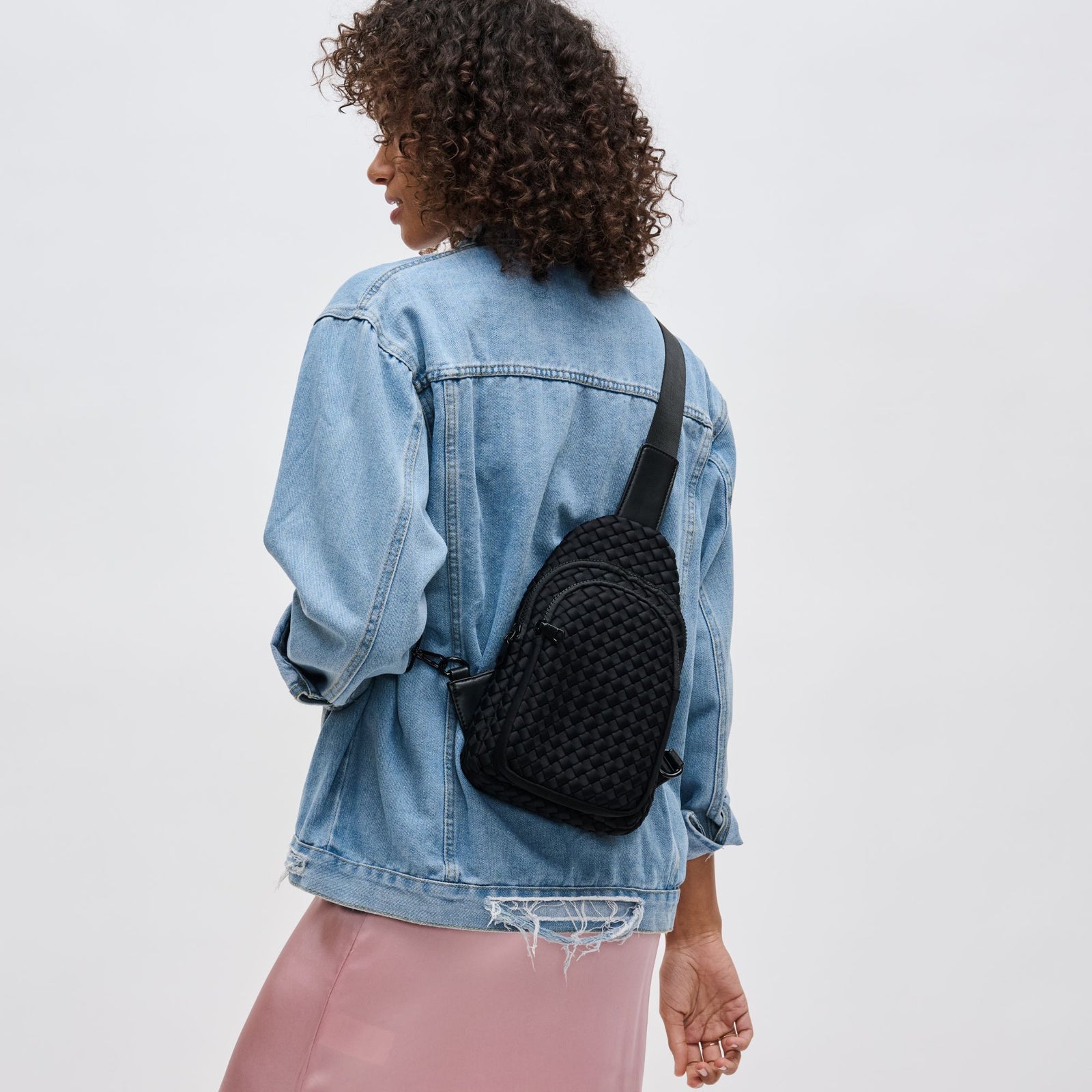 woman wearing a black woven sling bag