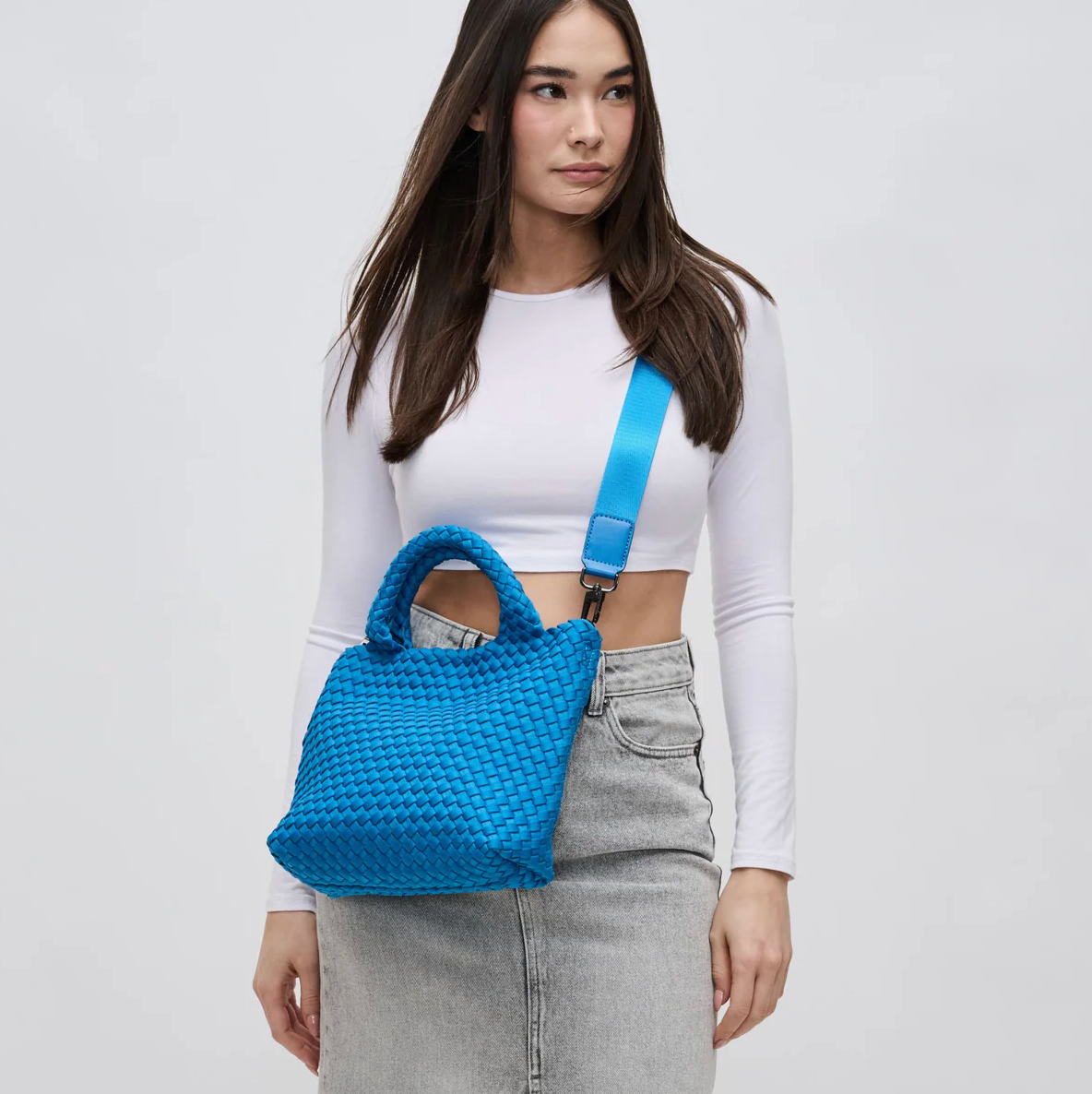model wearing a blue crossbody tote