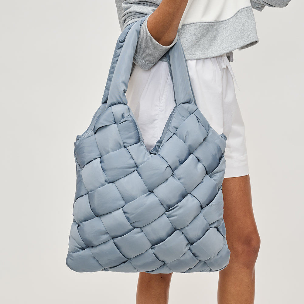 woman holding a blue quilted bag