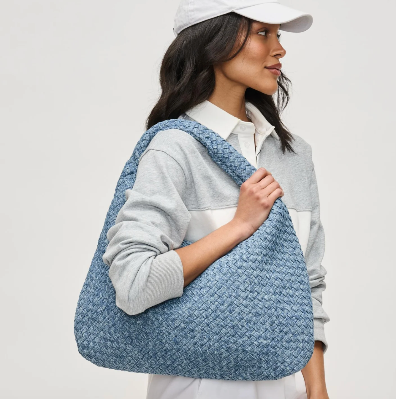 Woman holding a blue woven crossbody bag