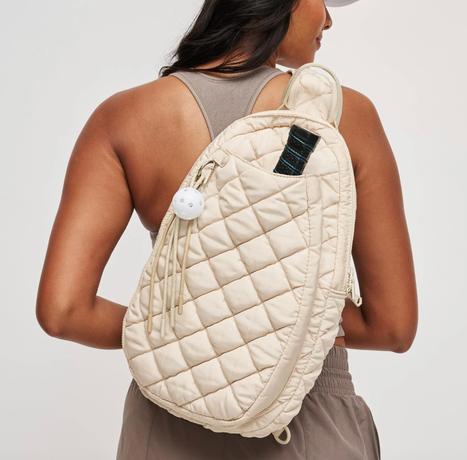 woman wearing a cream pickleball sling backpack