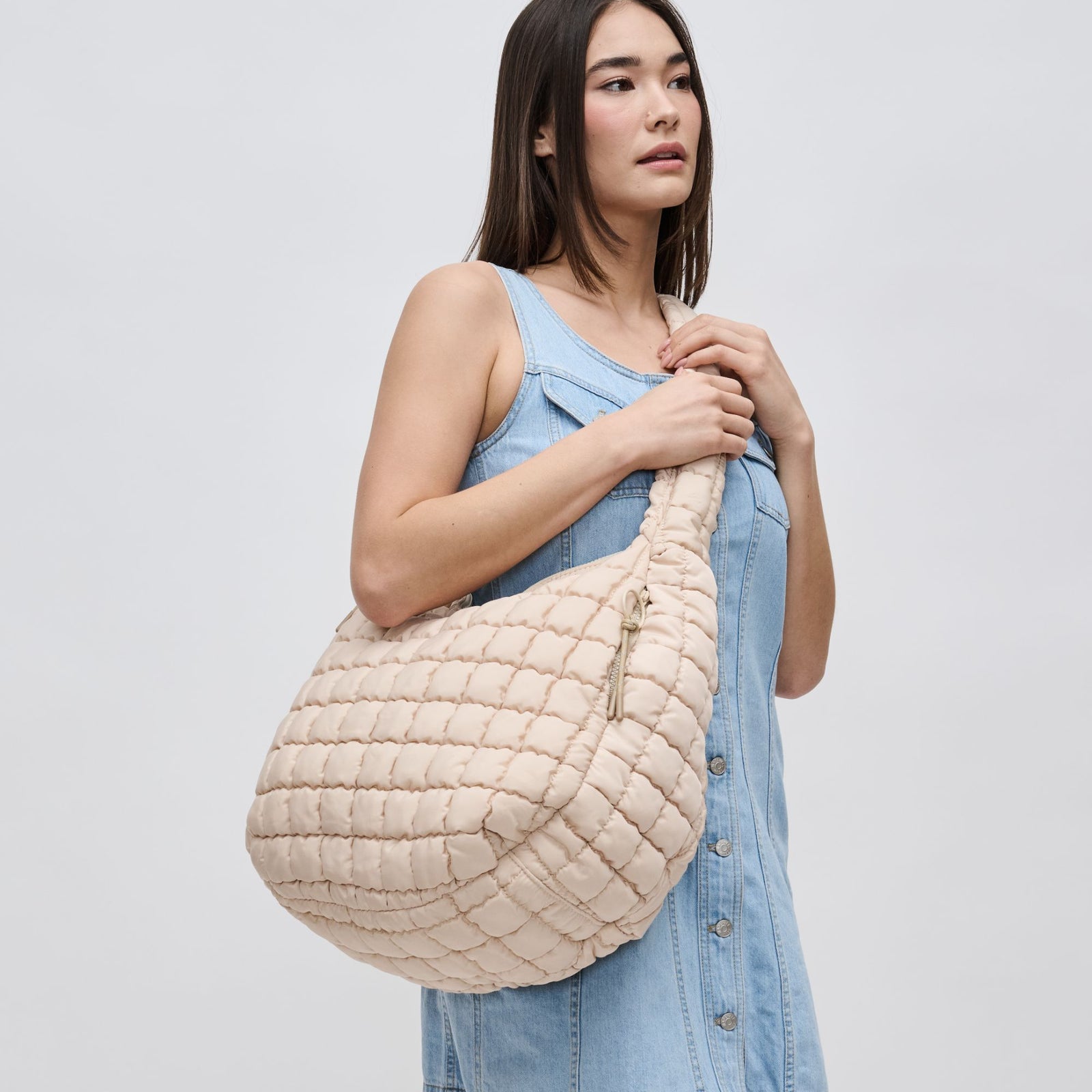 Woman holding a cream quilted bag