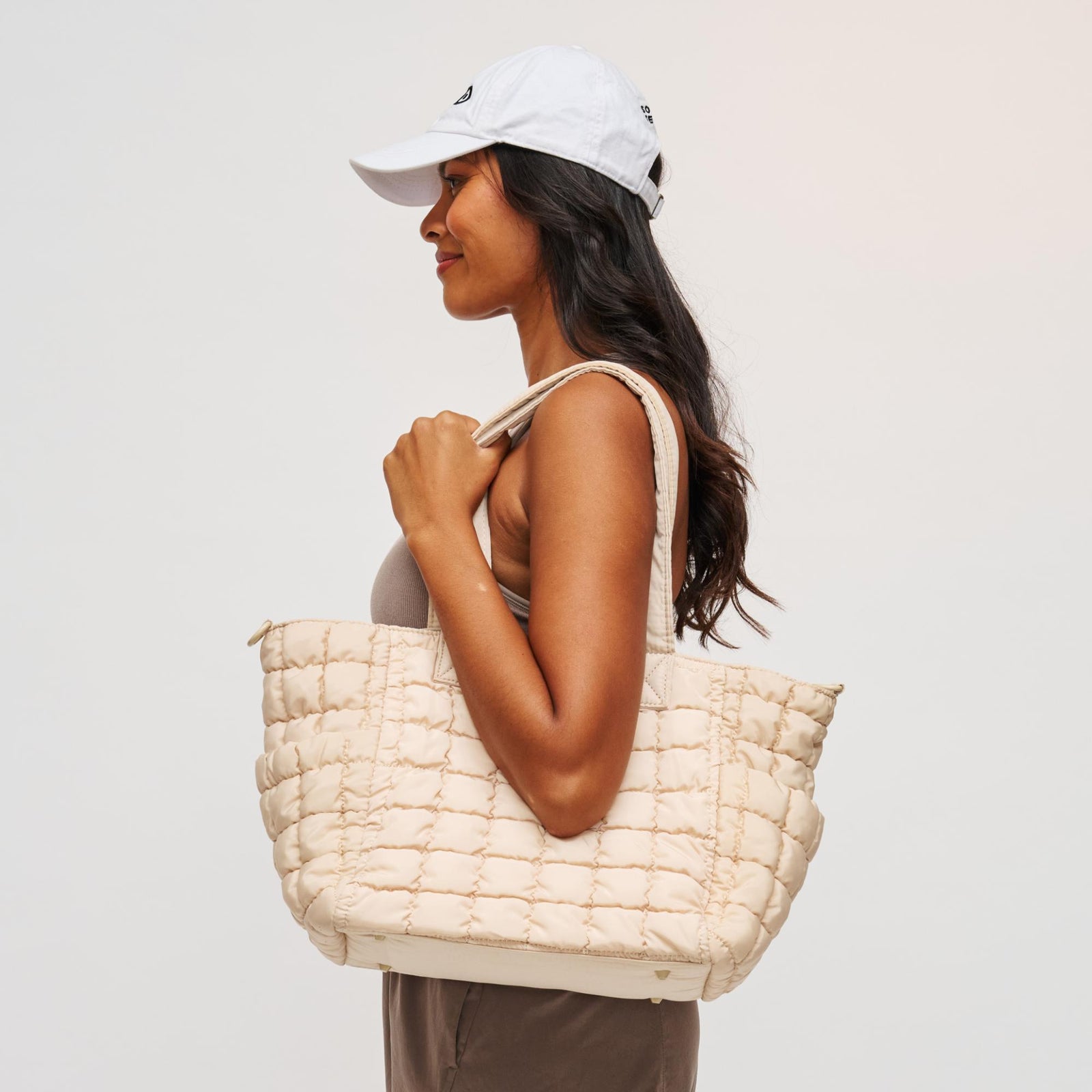 woman with a cream travel tote on her shoulder