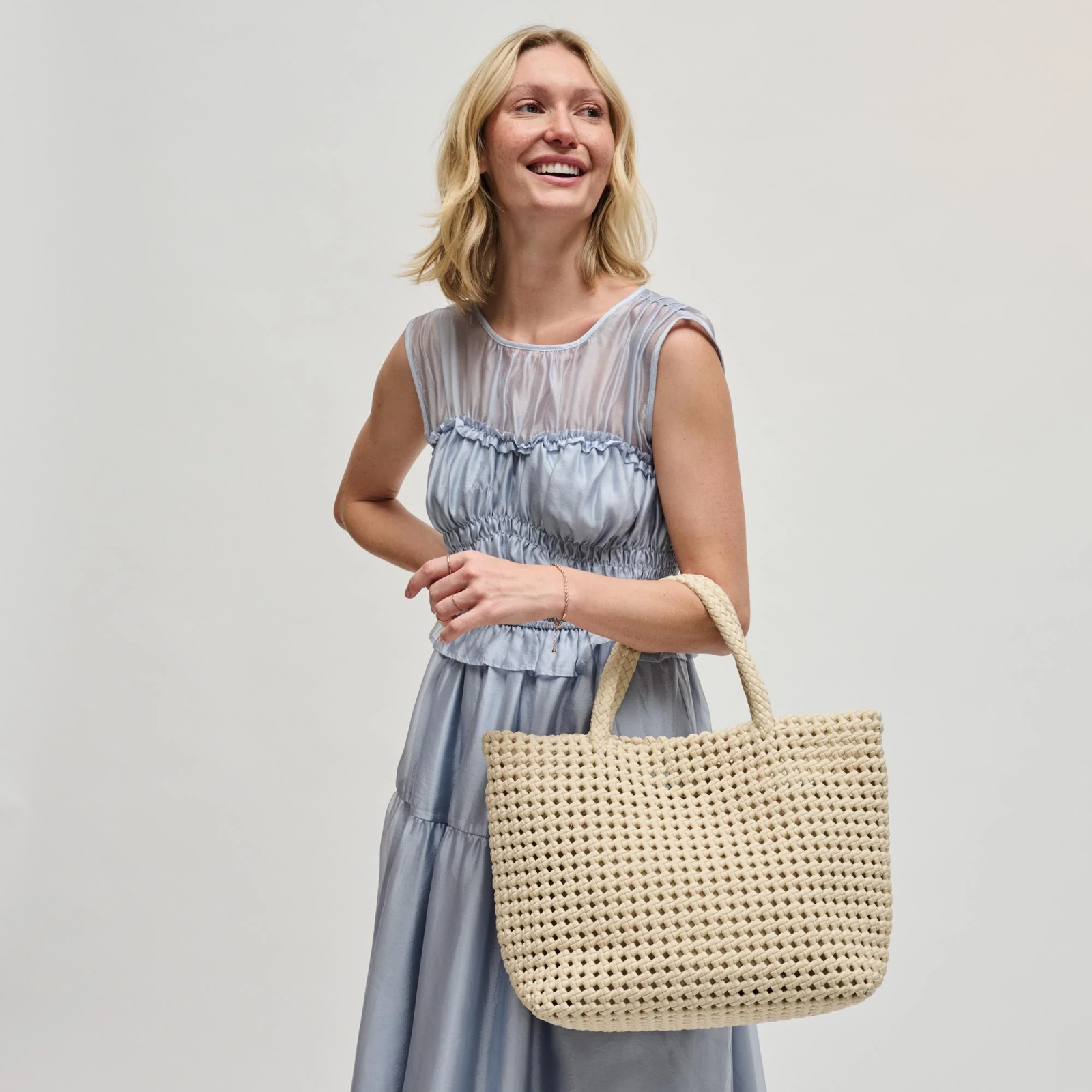 Woman carrying a cream woven purse