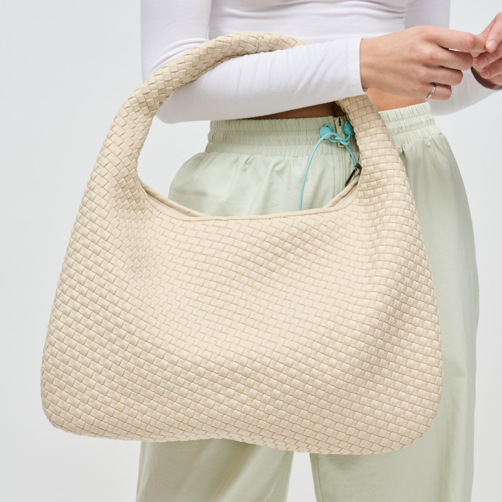 cream woven tote bag on a woman’s arm