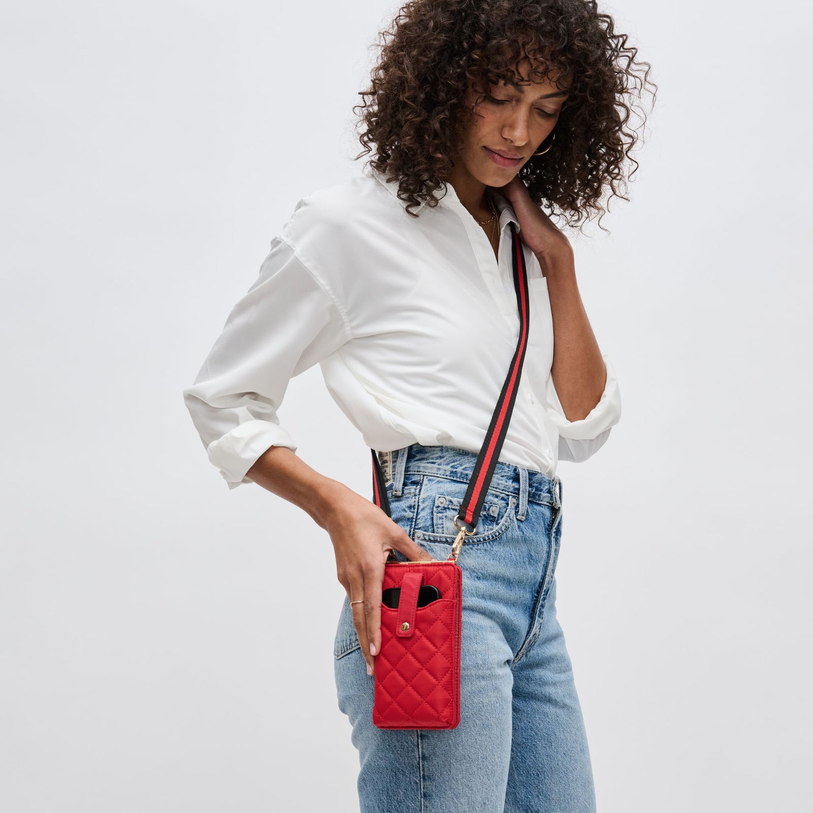 woman wearing a red quilted crossbody cell phone bag