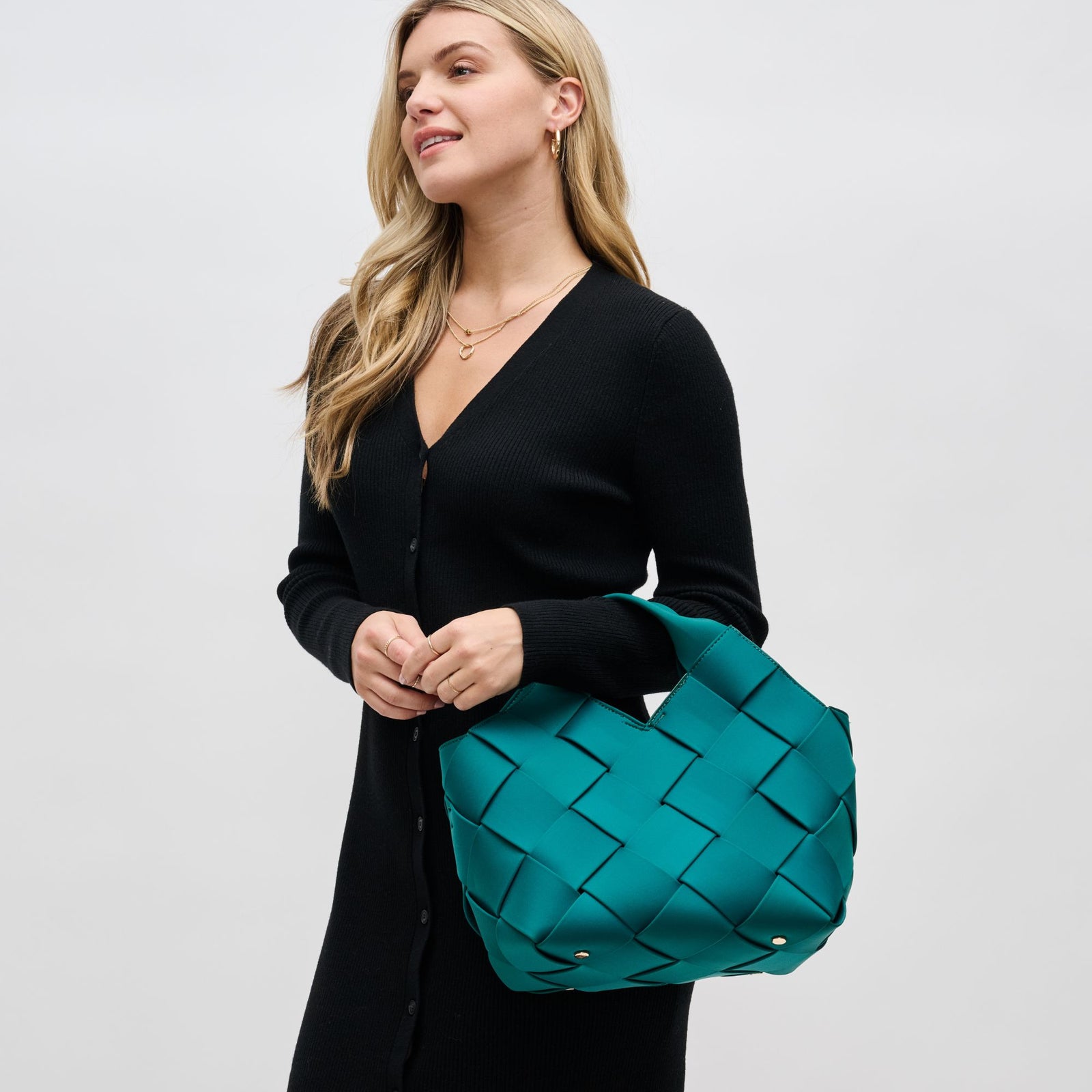 woman holding a green woven handbag