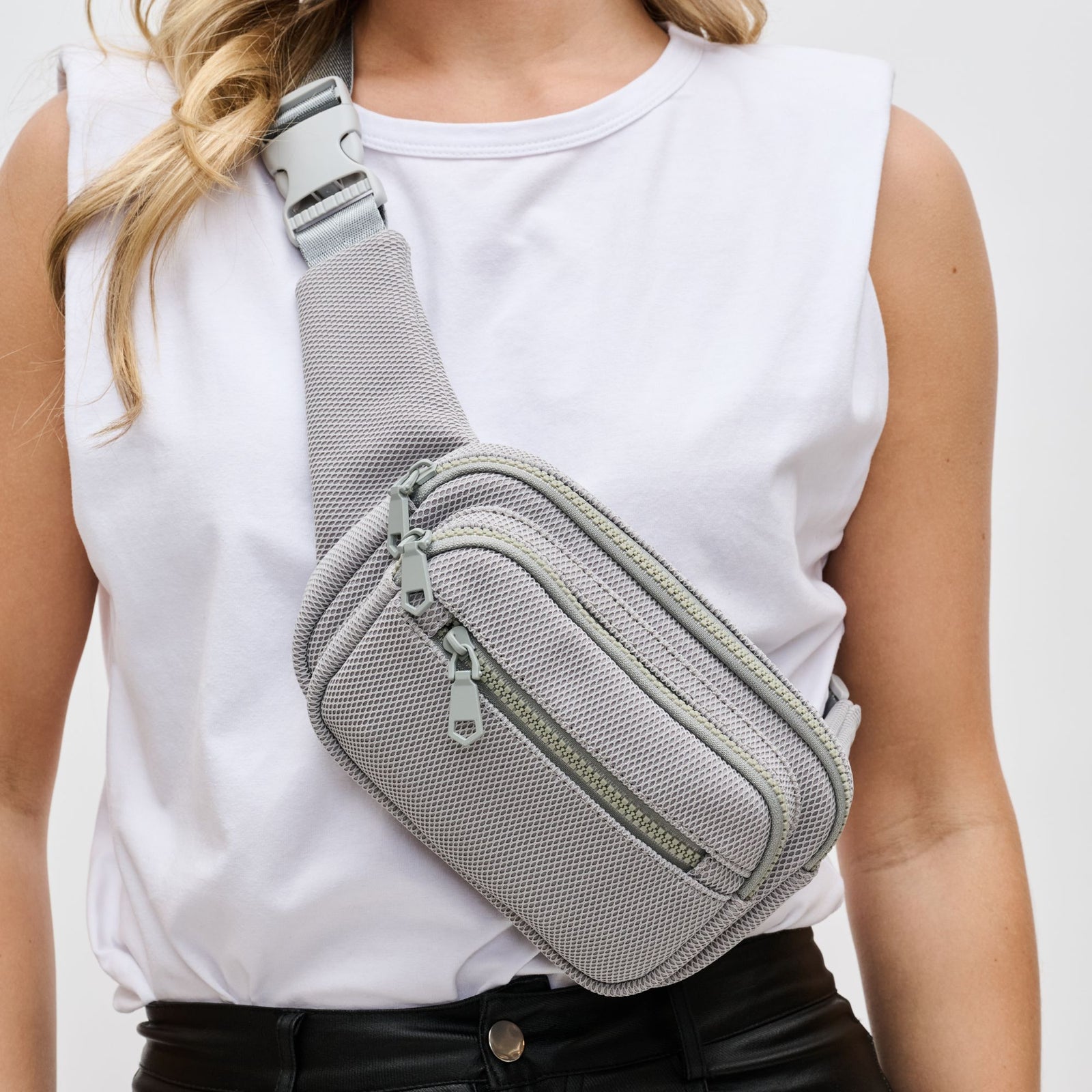 grey belt bag slung across a woman’s torso 