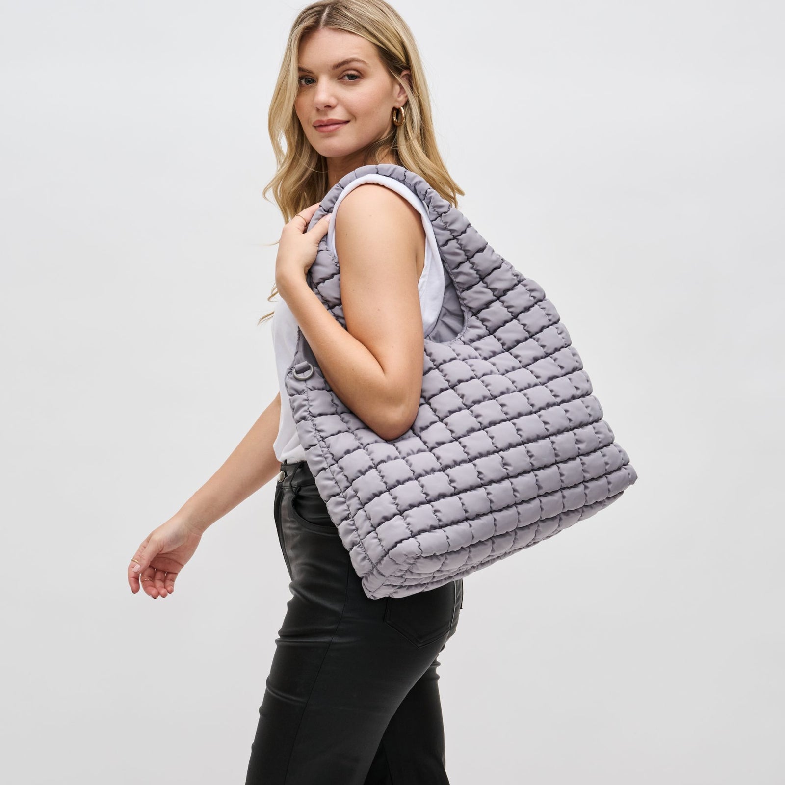 woman carrying a large grey quilted bag over her shoulder