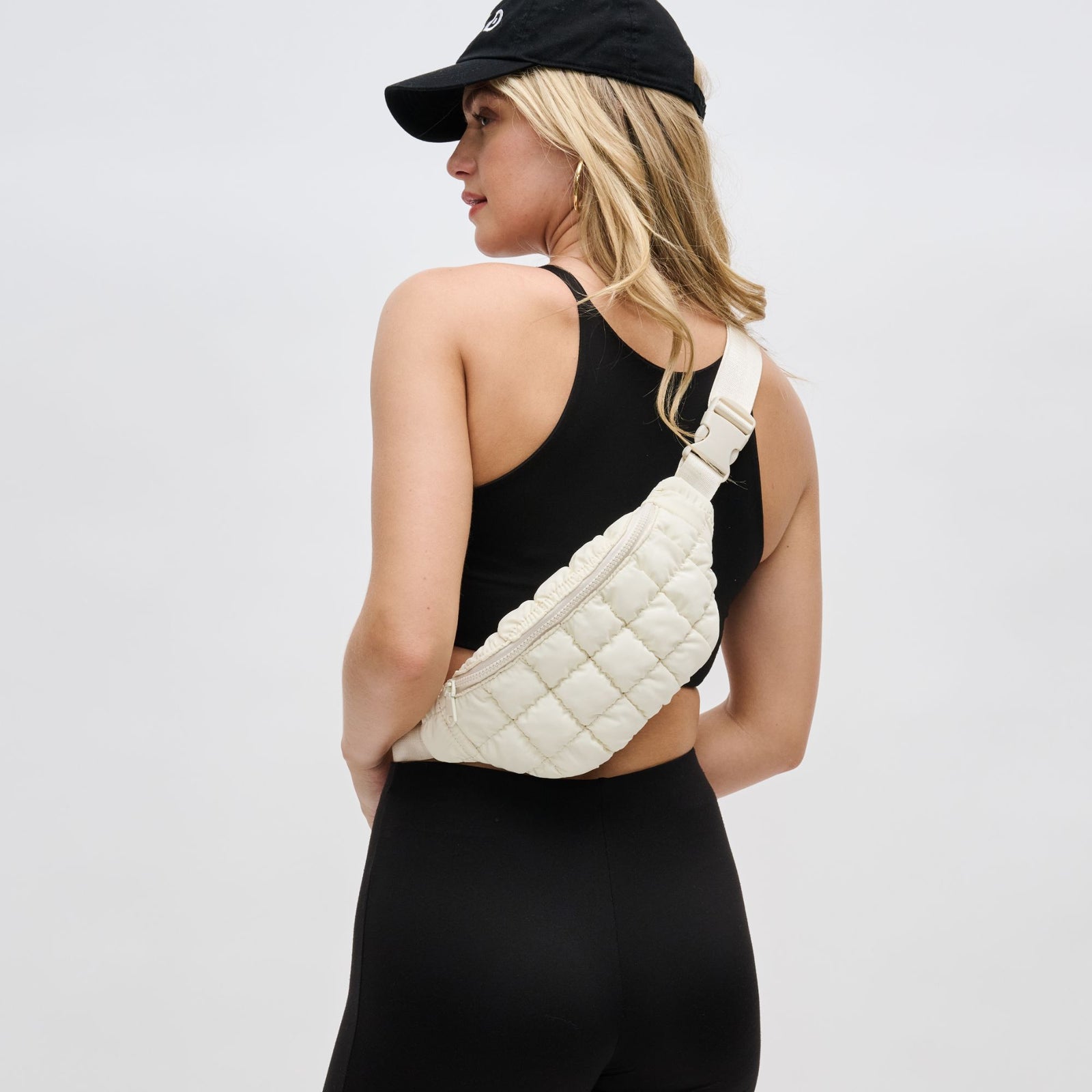 woman wearing an ivory belt bag across her back