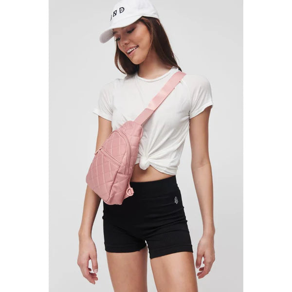 model wearing a light pink sling backpack
