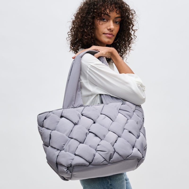 a model carrying a large puffer-style gray tote bag