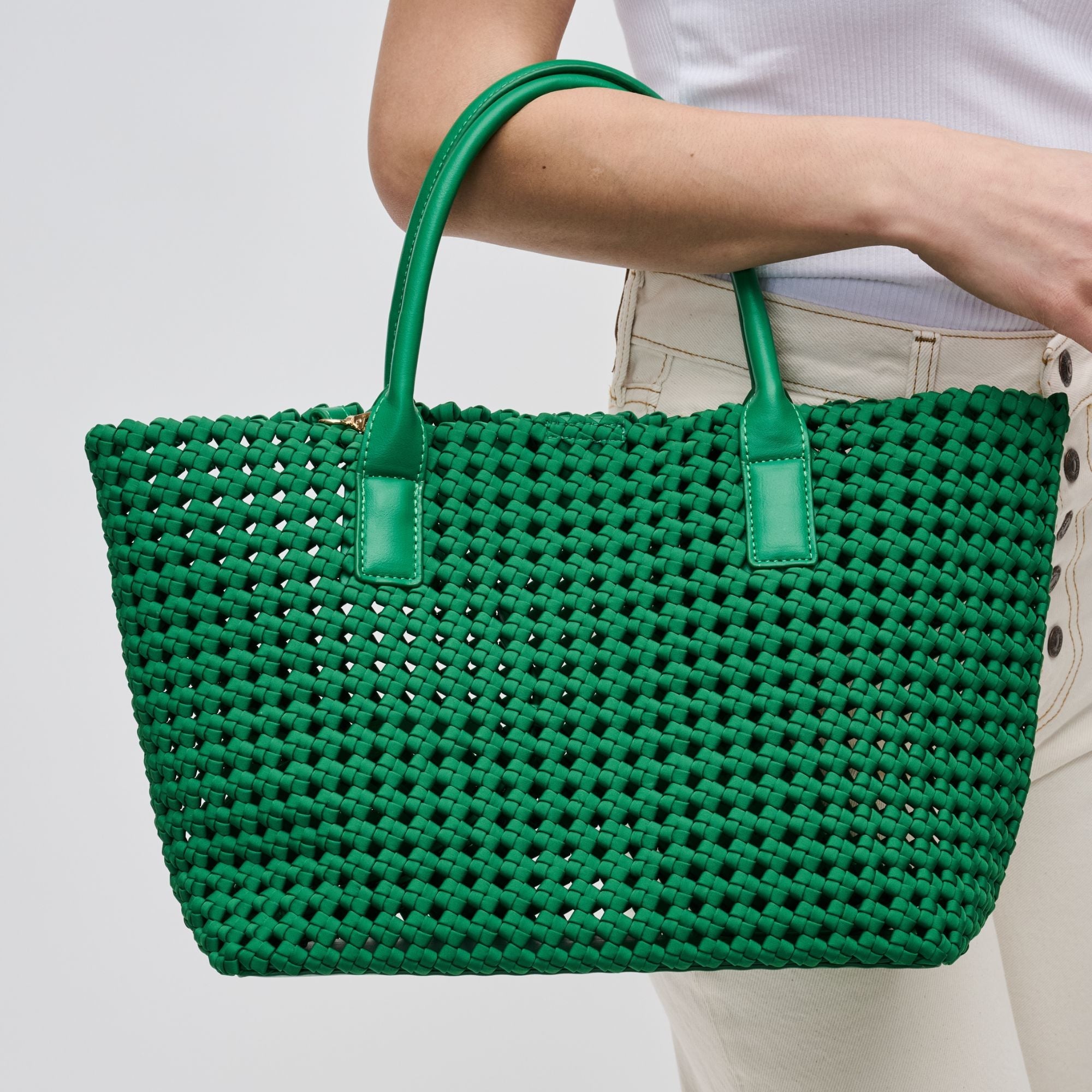 a model holding a woven green tote bag
