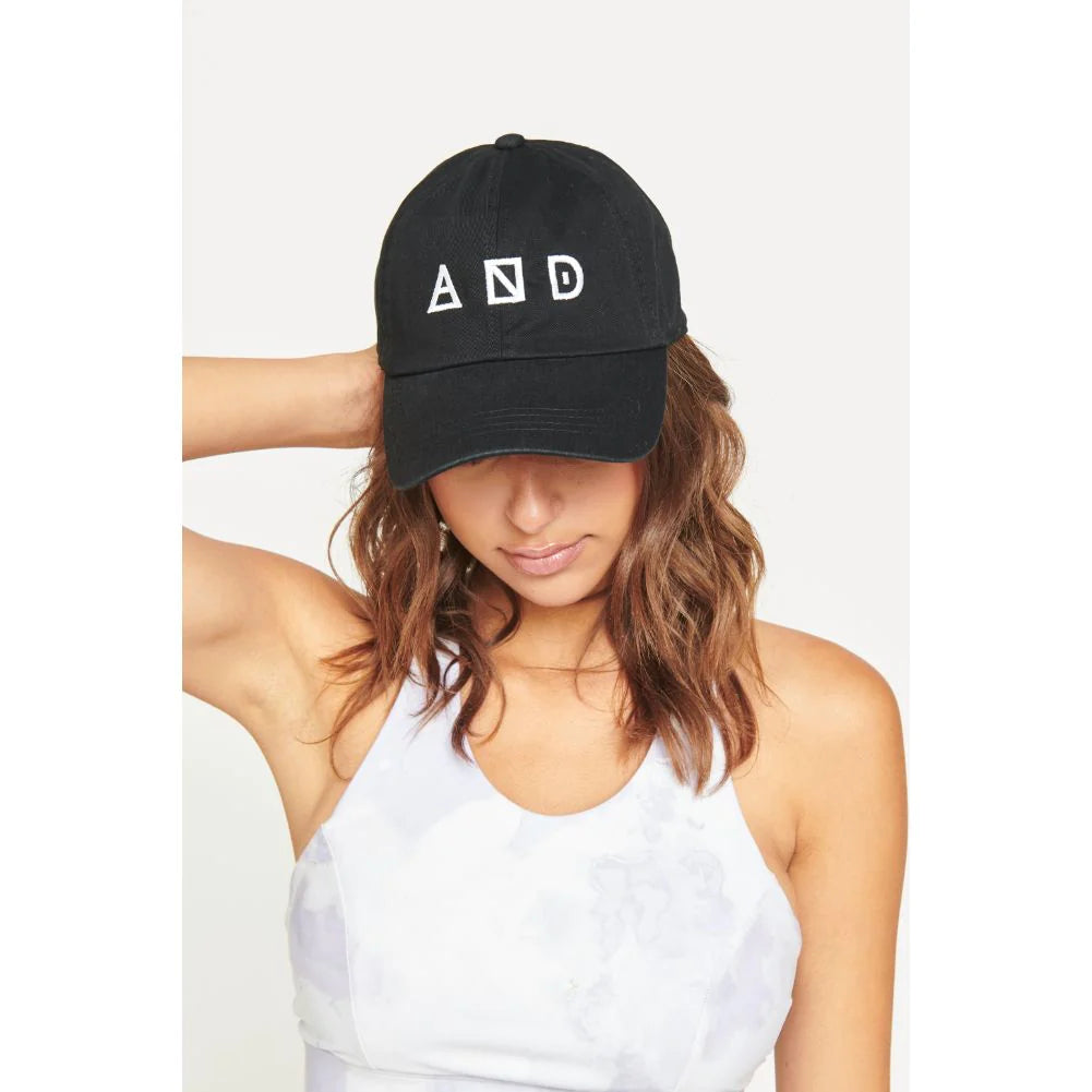a model wearing a Sol and Selene black baseball cap with white logo