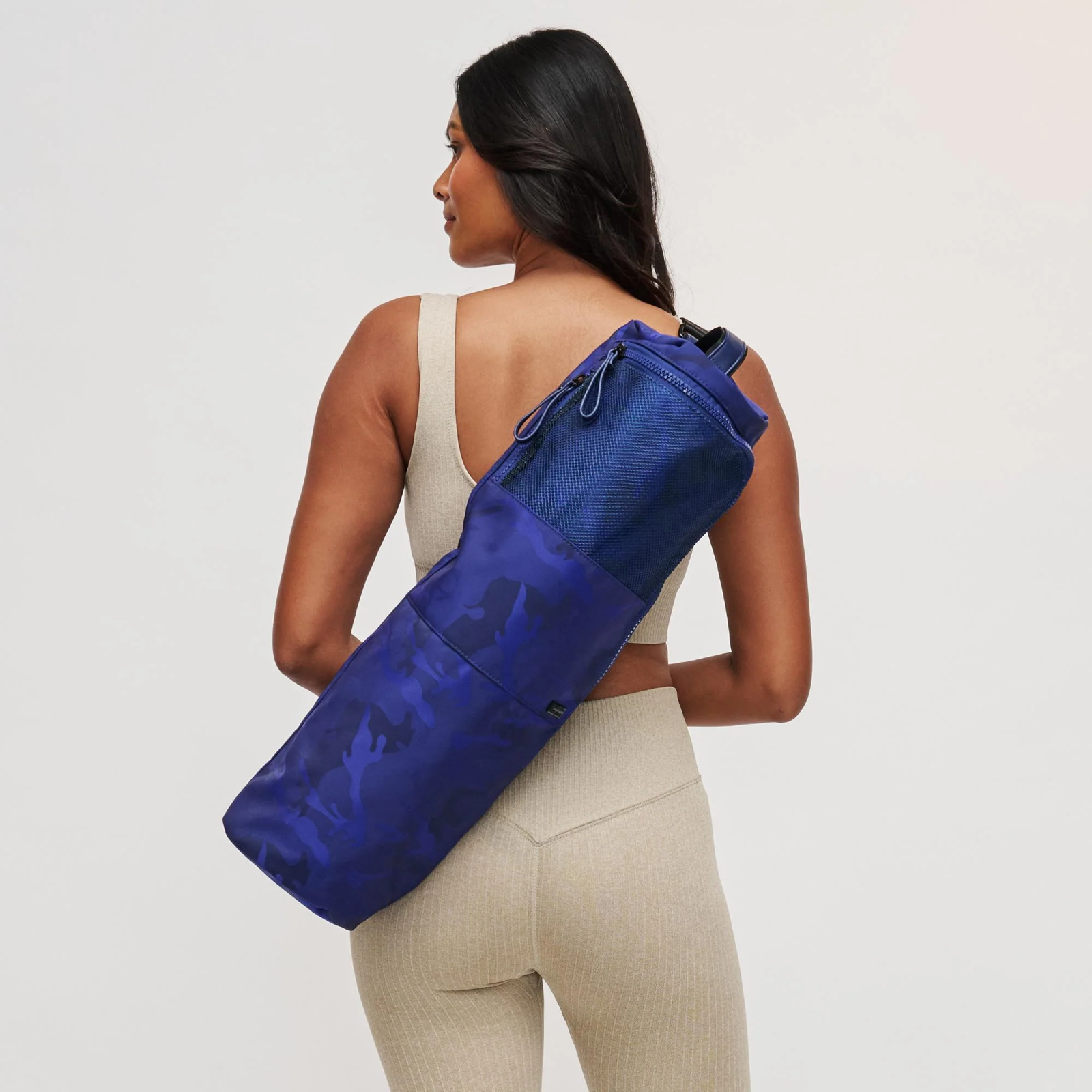 A mom with a blue yoga mat bag on her back