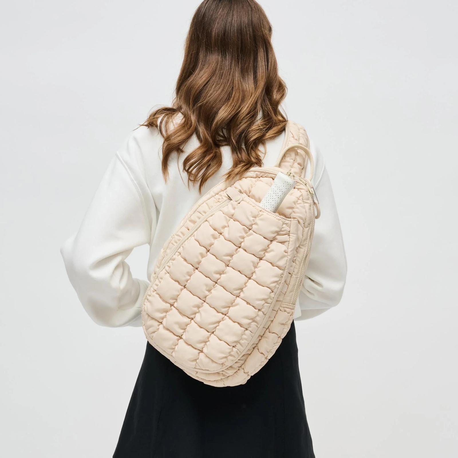 A mom with a cream pickleball bag on her back