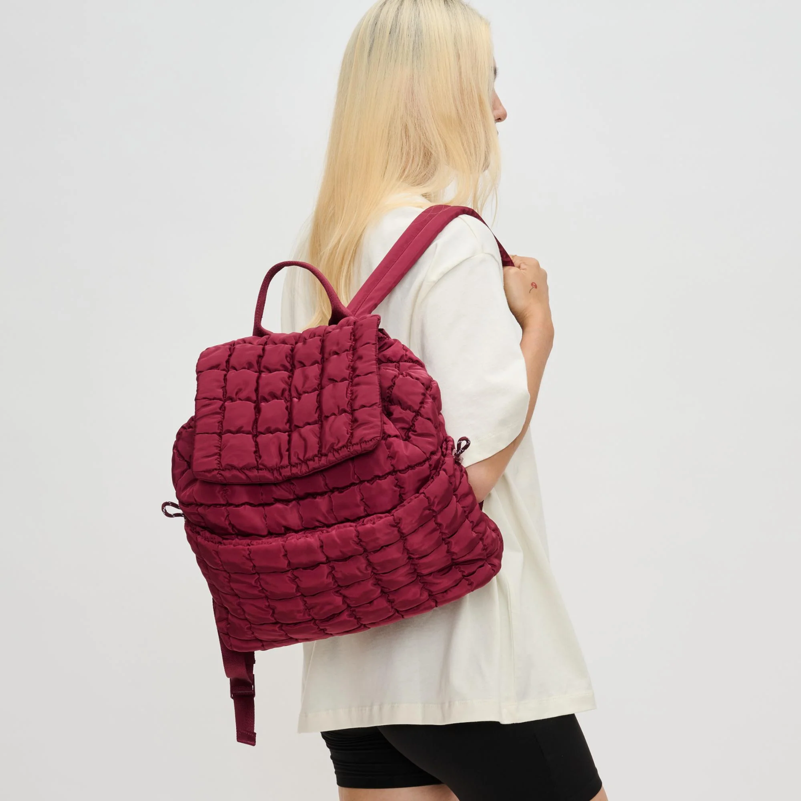 A mom holding a red quilted backpack
