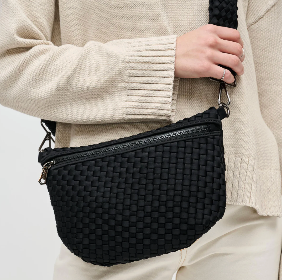 Woman holding an olive crossbody bag with interchangeable strap
