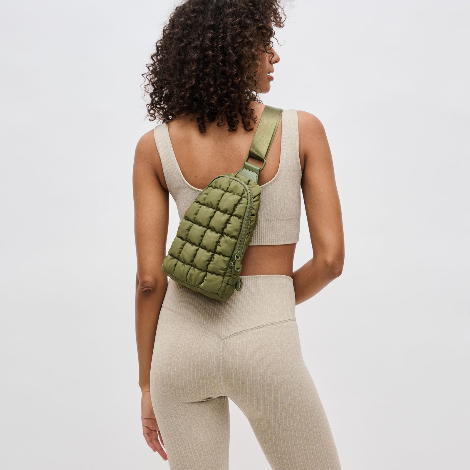 woman wearing an olive green quilted sling bag