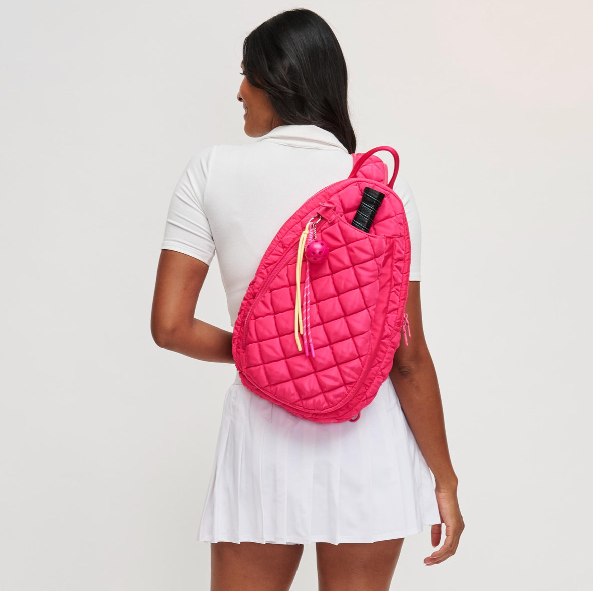 woman wearing the pink match point sling backpack
