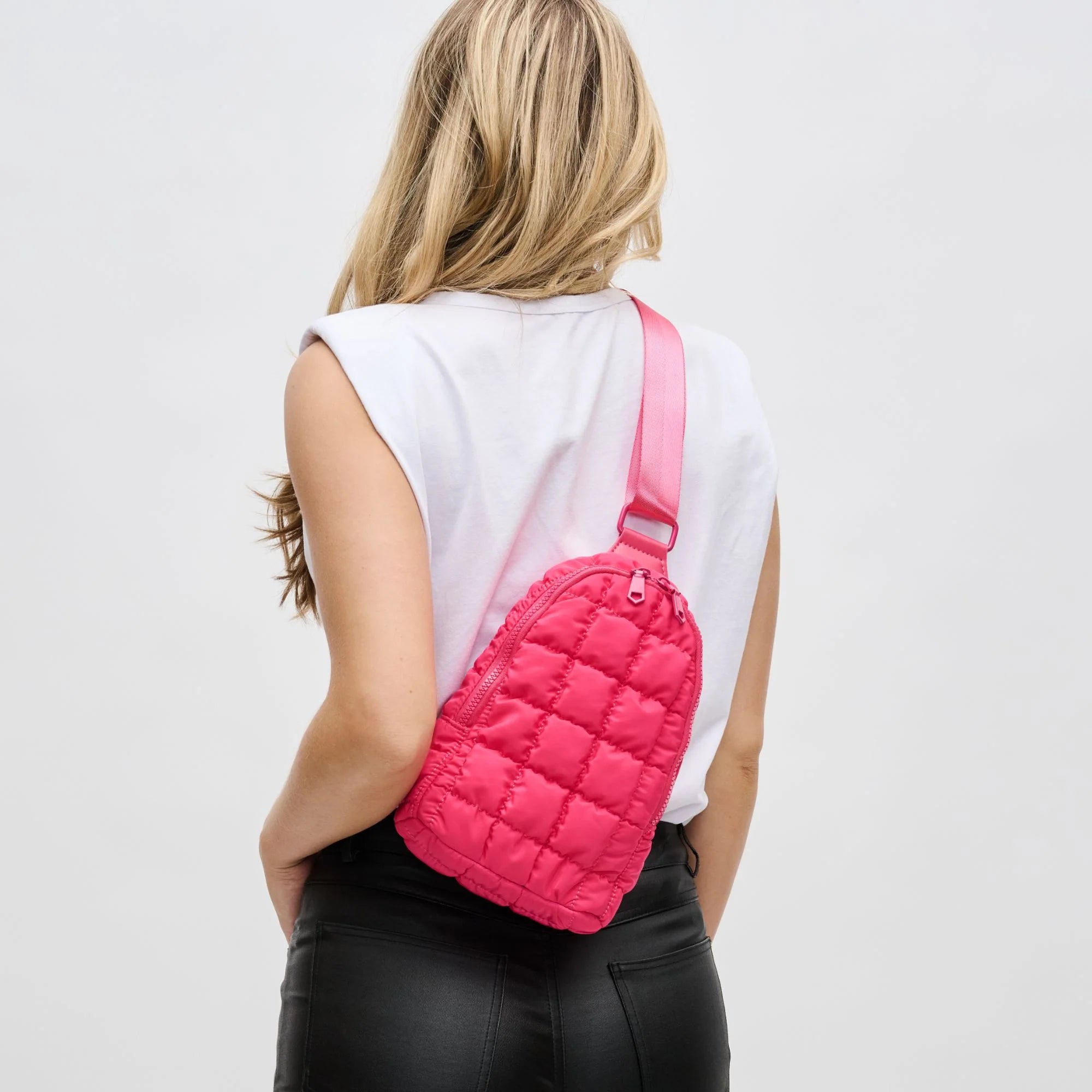 model wearing a pink sling quilted backpack