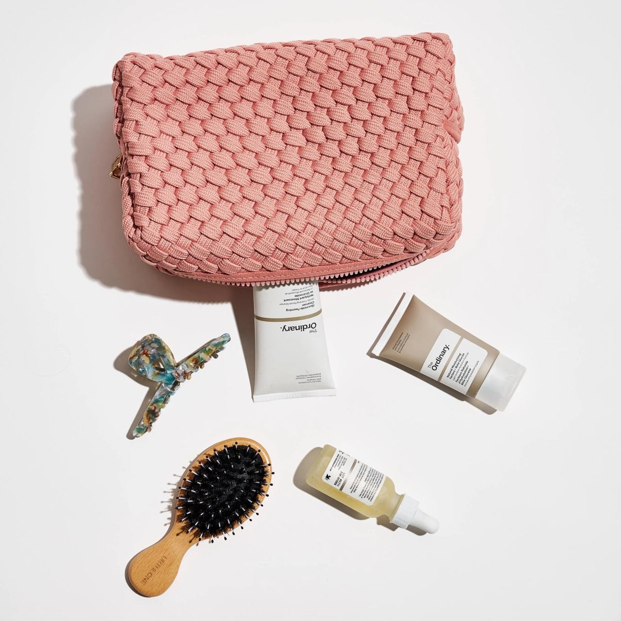 Pink travel pouch arranged with cosmetics