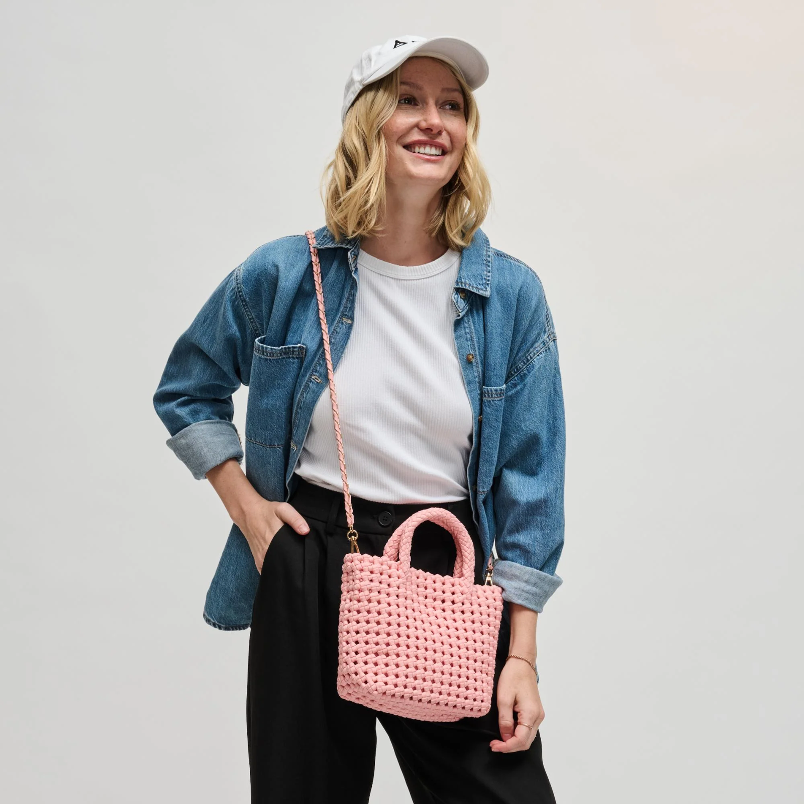 Woman carrying a pink woven crossbody bag