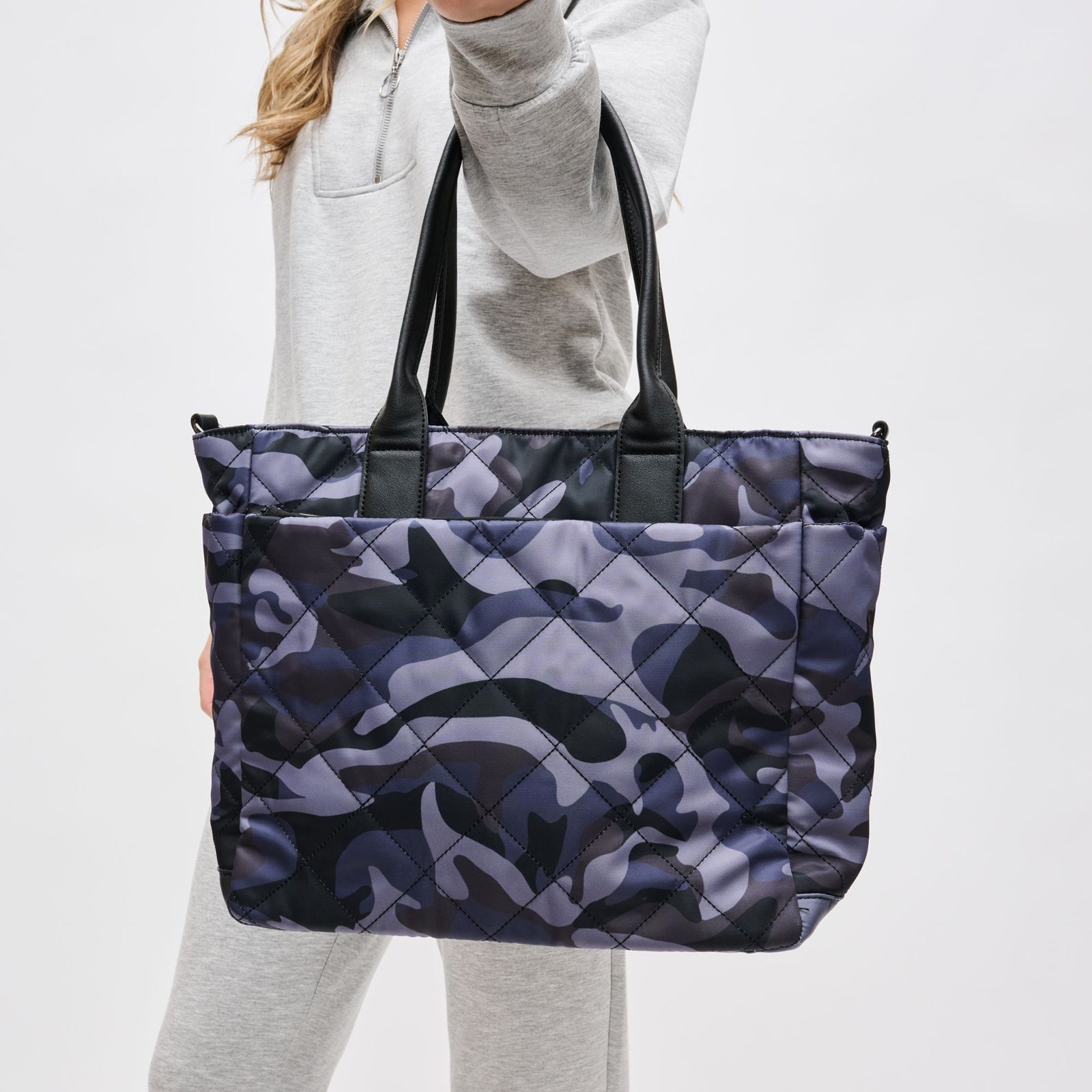 Woman carrying purple camouflage quilted tote bag