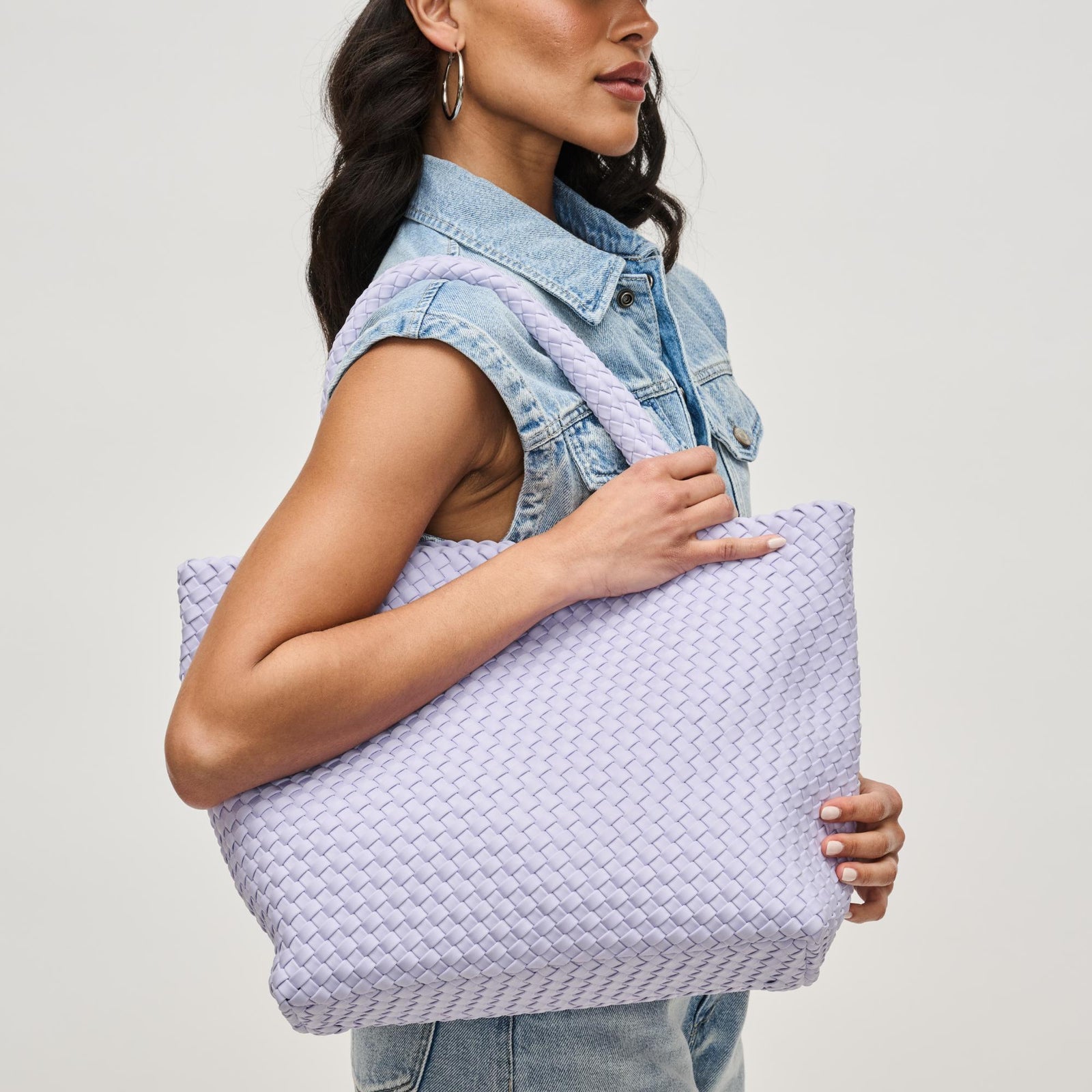 Lady in denim with a purple woven bag held on her shoulder