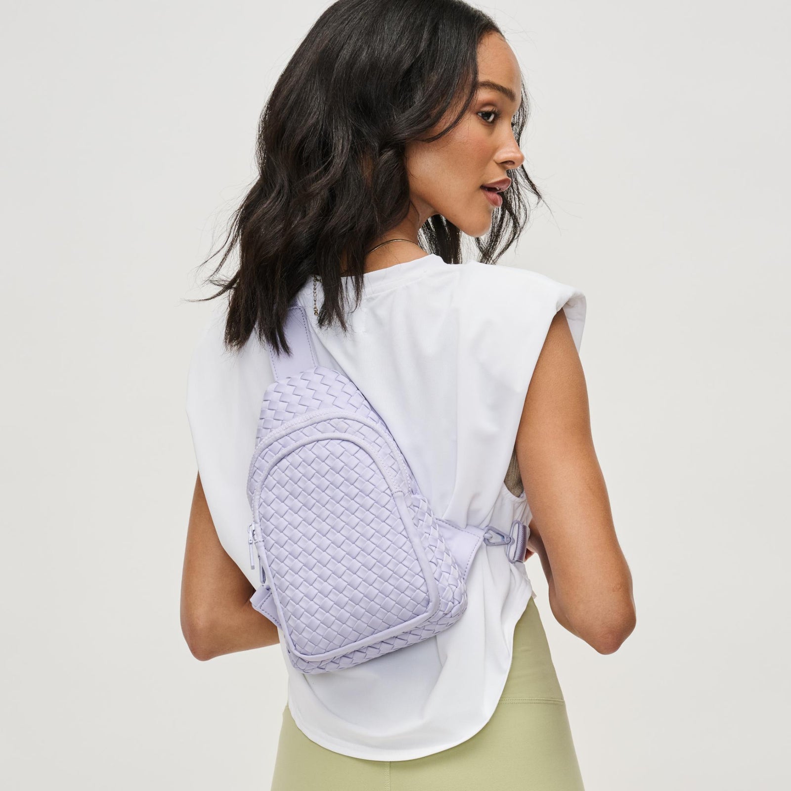 woman wearing purple woven sling backpack bag