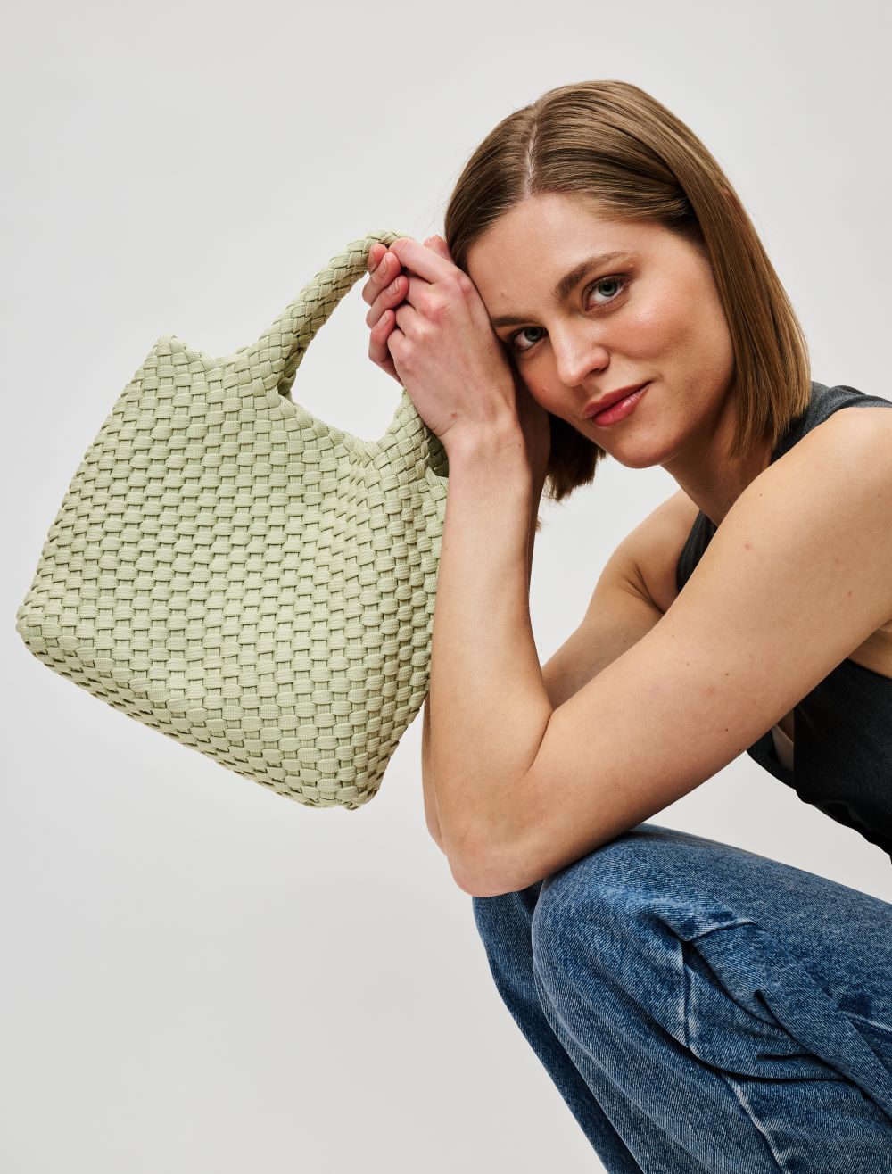 woman holding a sage green tote bag