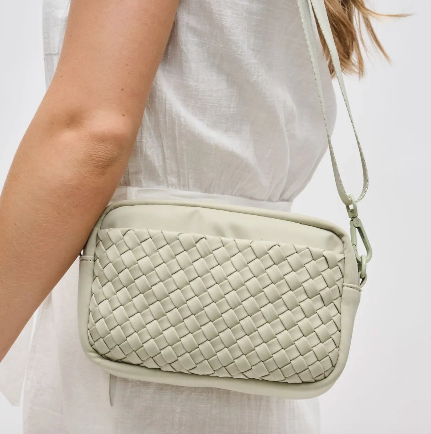 Woman wearing a sage woven crossbody bag