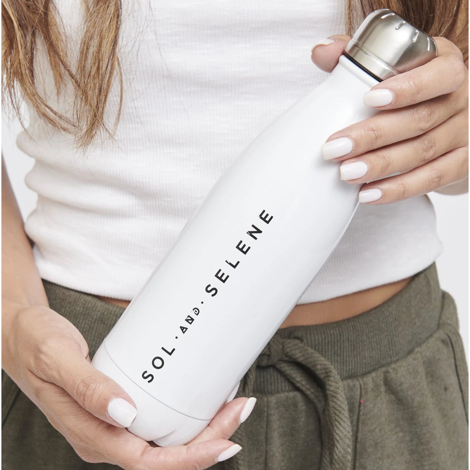 woman holding a white Sol and Selene-branded water bottle