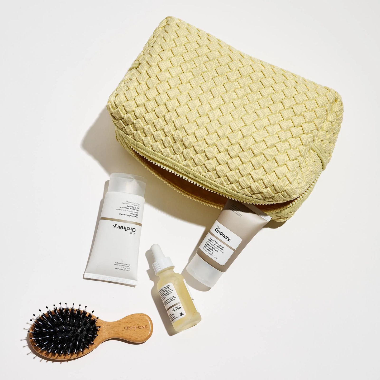 A yellow woven makeup bag with beauty products